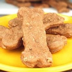 a yellow plate topped with dog treats on top of a table next to other food items