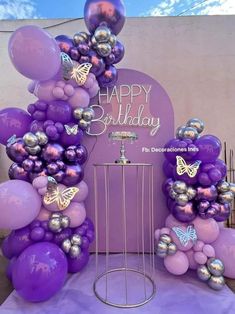 purple balloons and butterflies are on display at a birthday party with a sign that says happy birthday