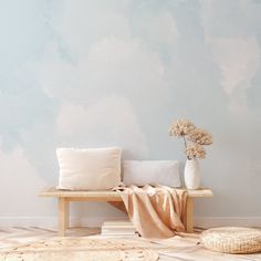 a wooden bench sitting in front of a blue wall with clouds painted on the walls