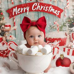 a baby is sitting in a cup with marshmallows on it and christmas decorations around her