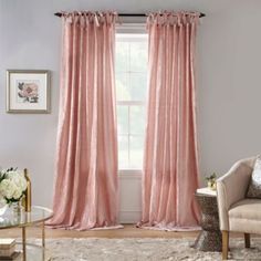 a living room filled with furniture and a window covered in pink drapes next to a chair