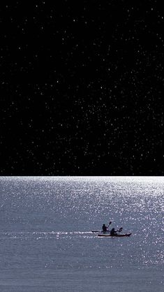 two people in a row boat on the water at night with bright stars above them