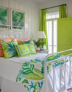 a white bed topped with lots of pillows next to a green door and window sill