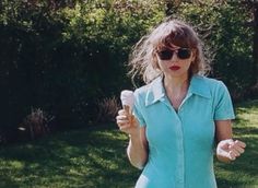 a woman holding an ice cream cone in her right hand and wearing sunglasses on the other