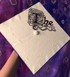 a person wearing a purple and white graduation cap with the letter b in black on it