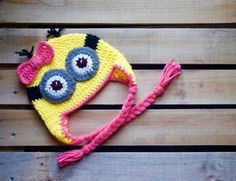 a crocheted hat with eyeballs on it sitting on top of a wooden bench