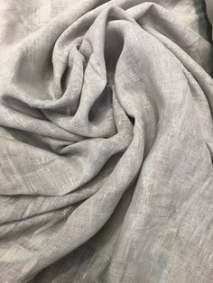 a close up view of the fabric on a white bed spread with grey linens