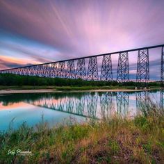 a large bridge over a body of water under a purple and blue sky with clouds