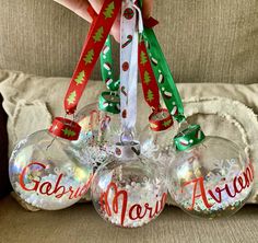 three christmas baubles with ribbons hanging from them on a couch in front of a pillow