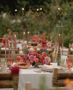 the table is set with flowers, candles and watermelon slices for an elegant dinner