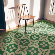 a wooden chair sitting on top of a green rug in front of a window next to a door