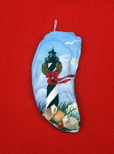 an ornament with a lighthouse and sea shells hanging from it's side