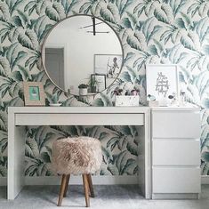 a vanity with a mirror, stool and plant wallpaper