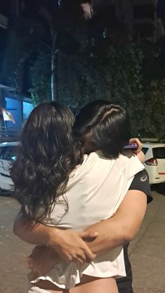 two people hugging each other on the street