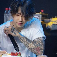 a man with tattoos cutting into a cake