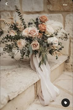 a bridal bouquet sitting on top of a stone ledge next to a brick wall