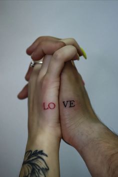 two people holding hands with the word love tattooed on them