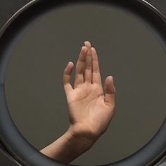 a person's hand is in the middle of a circular black object, with their fingers raised up