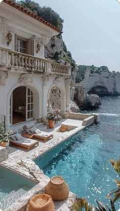 an outdoor swimming pool with chaise lounges next to the water and cliffs in the background