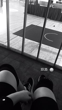 a person is sitting on the floor in front of a basketball court and has their legs crossed