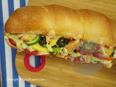 a sub sandwich cut in half on top of a cutting board next to a knife