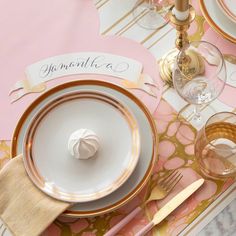 the table is set with pink and gold plates, silverware, and napkins