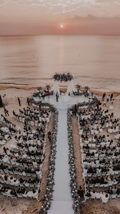 an aerial view of a wedding ceremony setup on the beach at sunset, with ocean and sky in the background