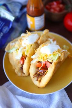 two tacos on a yellow plate with condiments