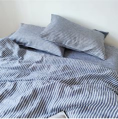 an unmade bed with blue and white striped sheets