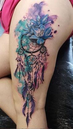 a woman's thigh with watercolor tattoos on it