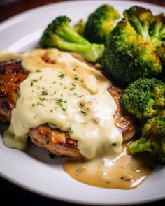 a white plate topped with meat covered in gravy and broccoli