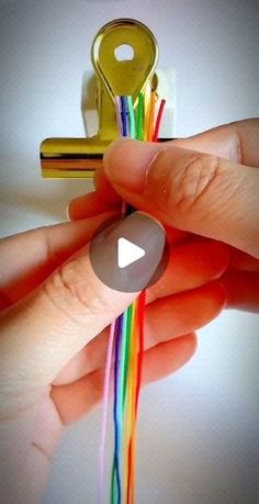 a person is holding a colorful string with a key in the background