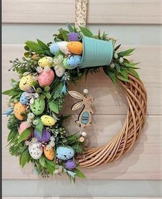 a wreath with an easter decoration hanging on the wall next to a blue bucket filled with eggs