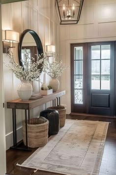 a foyer with a rug, mirror and vases