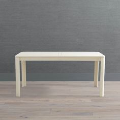 a white table sitting on top of a hard wood floor next to a gray wall