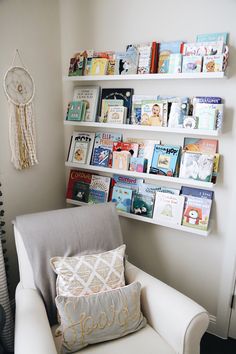 a white chair sitting in front of a book shelf filled with children's books