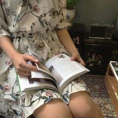 a woman is sitting down reading a book