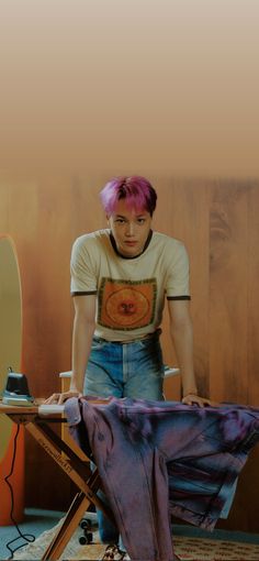 a man with pink hair standing next to a table