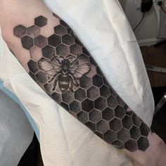 a man's arm with a honeycomb and a bee tattoo on the arm