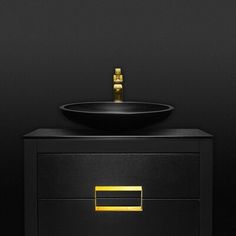 a black sink with gold trim on it and a dark wall in the back ground