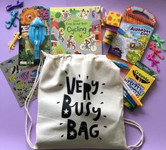 a bag filled with children's books and toys on top of a purple surface