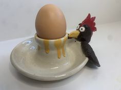 an egg in a cup with a chicken sticking its head into it's shell