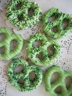 four donuts with green frosting and sprinkles on a doily