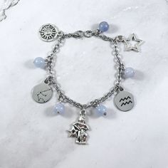 This Aquarius themed charm bracelet is the perfect accessory to showcase your sun sign. Charms included: Sun Aquarius Constellation  Aquarius Water Bearer Aquarius Symbol Star 5 aquamarine beads are included between the charms. (Gemstone can be substituted upon request.) Comes in three sizes: Small: 6.5 inches (with extra rings at the end to expand up to 7.5 inches.) Standard: 7.5 inches Large: 8.5 inches Secures with a lobster clasp. Chain is stainless steel. Charms are made with zinc alloy. Beads are natural gemstones. All materials are lead and nickel free.  Comes in a jewelry box so it would be ready to be given as a gift! Message me of you would like to substitute any of the charms. If you have any questions or need more quantities than are currently available, please message me. Warn Silver Zodiac Sign Bracelet, Silver Zodiac Sign Symbolic Bracelets, Silver Zodiac Sign Symbolic Bracelet, Symbolic Zodiac Sign Bracelet Jewelry, Water Bearer Aquarius, Aquarius Water Bearer, Constellation Aquarius, Aquarius Jewelry, Sun Aquarius