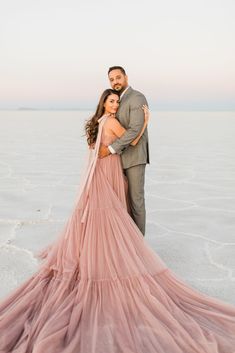 a man and woman standing in the middle of a salt flat with their arms around each other