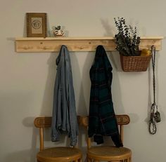 a couple of chairs sitting under a shelf with coats hanging on it's hooks