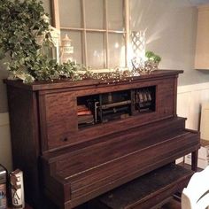 an old piano sitting in front of a window with plants growing on top of it