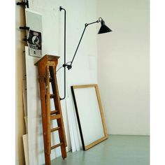 an old ladder leaning against the wall next to a framed photograph and a floor lamp