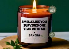 a candle that is sitting on top of a wooden board with a label reading smells like you survived one year with me