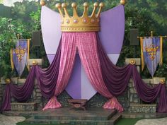 a stage set up with purple drapes and gold crown